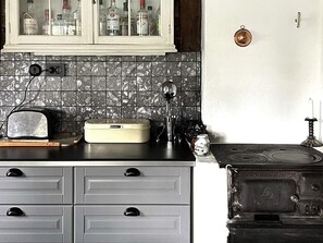 A kitchen with a vintage stove, a toaster, a cabinet with bottles, and a tiled backsplash. - 4 Star Holiday Home in Tronodal (Trönödal)