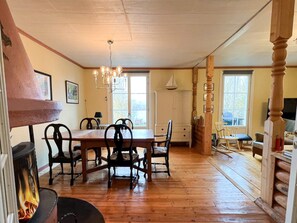 A dining area with a wooden table and chairs, a fireplace, and a chandelier. - 4 Star Holiday Home in Tronodal (Trönödal)