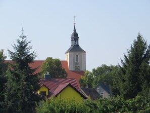 A church with a tall steeple and a clock on its side. - Holiday Home Sonnentau (Burg (Spreewald))