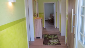 A hallway with green walls, wooden flooring, and a brown rug with a floral pattern. - Holiday Home Sonnentau (Burg (Spreewald))