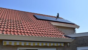 A house with a red-tiled roof, a solar panel, and a yellow-striped awning. - Holiday Apartment Mosselbank 95 (Ouddorp)
