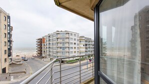 A balcony with a view of a coastal building complex, a road with cars, and a beach in the background. - Fiesole 201 Very Centrally Located in Koksijde (Koksijde)
