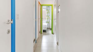 A hallway with white walls, a blue door on the left, and a green door at the end. - Fiesole 201 Very Centrally Located in Koksijde (Koksijde)