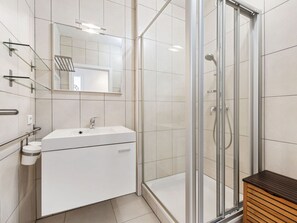 A modern bathroom with a glass shower enclosure, a white sink, and a wooden bench. - Fiesole 201 Very Centrally Located in Koksijde (Koksijde)