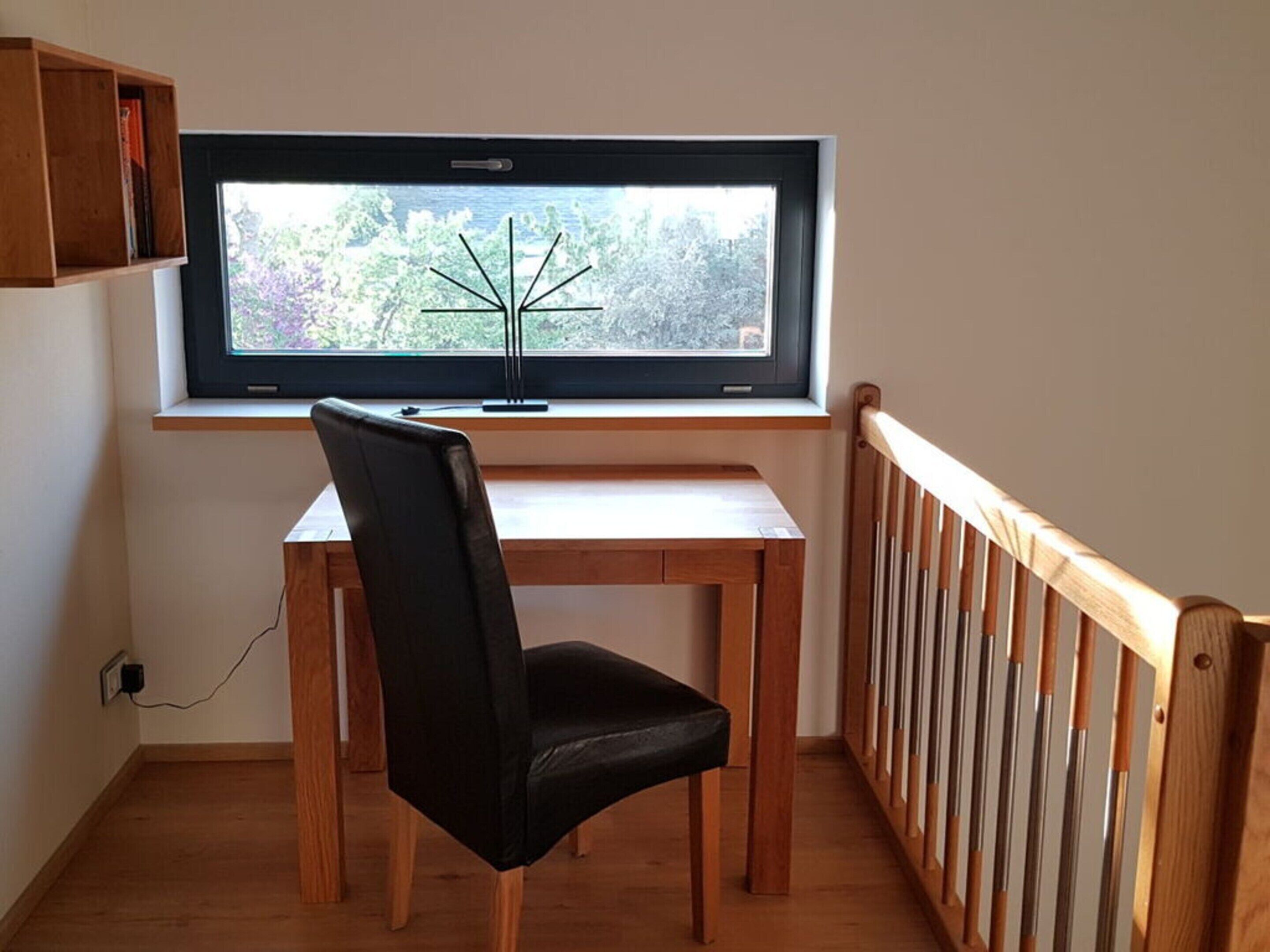 Une pièce comprenant un bureau, une chaise et une fenêtre donnant sur un arbre.