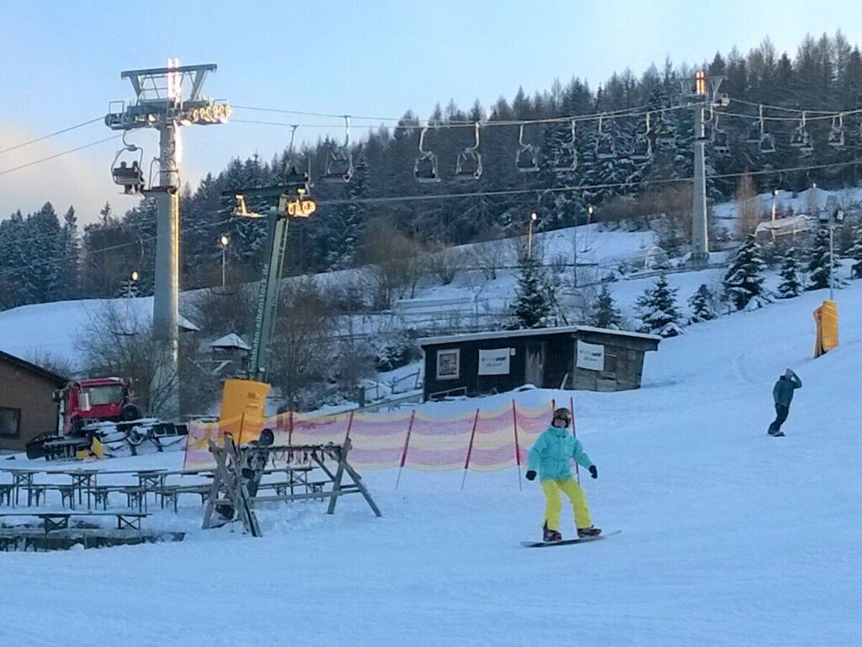 A ski slope with a chairlift, a small building, and a red truck.