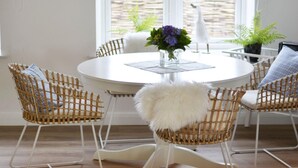 A round white table with wicker chairs and a white furry throw. - Holiday Apartment Domstag (Kronsgaard)