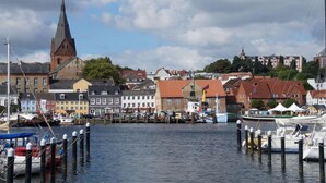 A harbor with boats docked, a prominent church steeple, and colorful buildings along the waterfront. - Holiday Apartment Domstag (Kronsgaard)