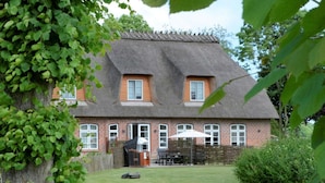 A house with a thatched roof, brick walls, and a well-maintained lawn. - Holiday Apartment Domstag (Kronsgaard)