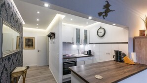 A modern kitchen with white cabinets, a wooden countertop, and a clock on the wall. - Hexengluck Hahnenklee (Goslar)