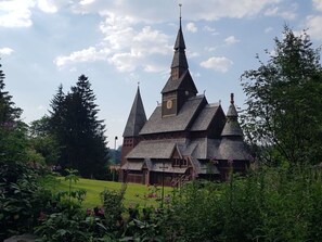 A traditional wooden building with a steeply pitched roof and multiple spires, surrounded by lush greenery. - Hexengluck Hahnenklee (Goslar)