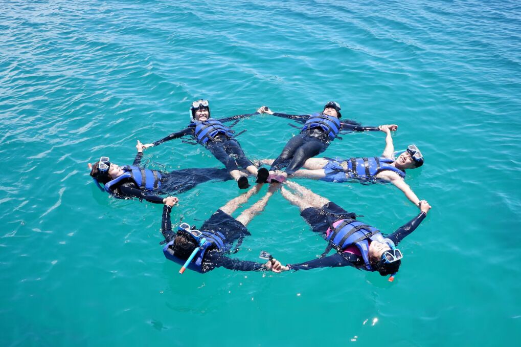 Cuatro personas buceando en círculo en aguas azules y cristalinas.