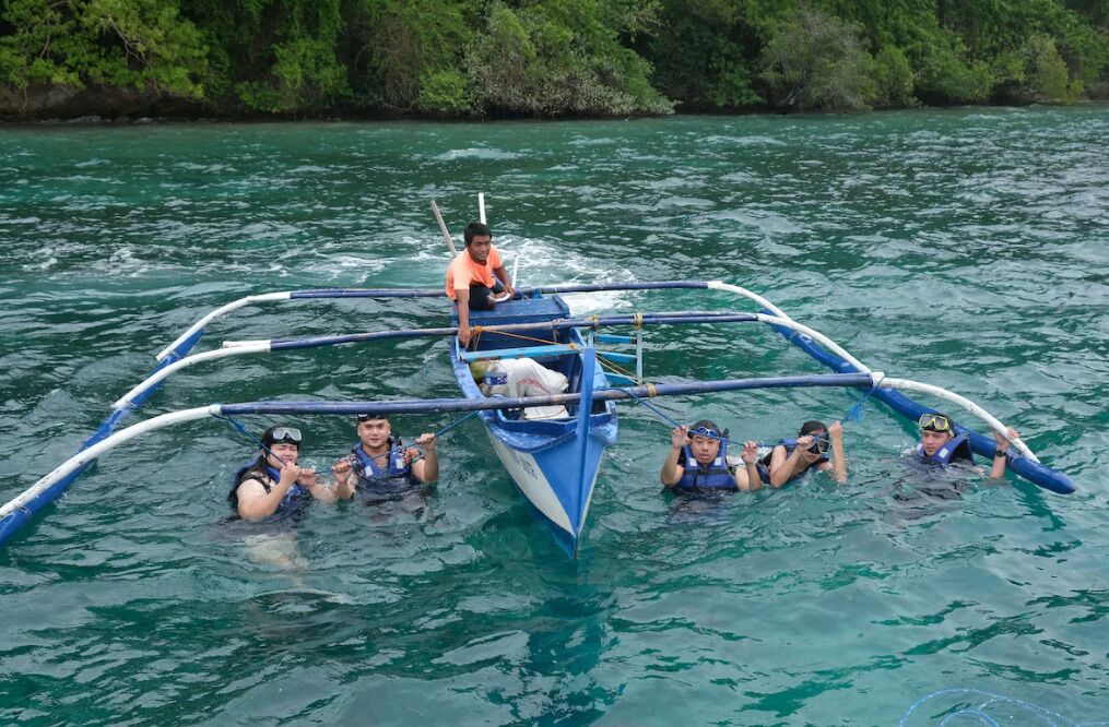 A group of people in a blue boat with a central platform, surrounded by water.