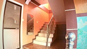 A staircase with a metal railing, a door with a mesh screen, and a wall with a mural. - Buena Lynne White Beach Puerto Galera (Puerto Galera)