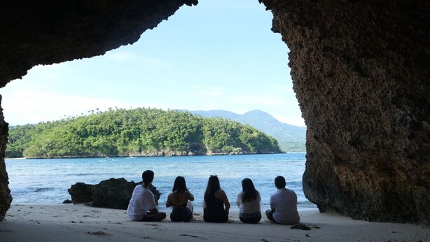 A group of people sitting on a beach with a view of a forested island and the sea. - Buena Lynne White Beach Puerto Galera (Puerto Galera)