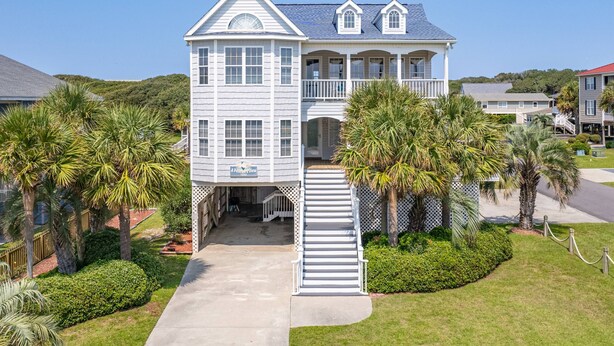 A large, two-story house with a covered front porch and a staircase leading to the entrance. - Gorgeous 2nd Row Home with Amazing Ocean Views, 2 Large Decks, Dog Friendly, Sleeps 12 (Oak Island)