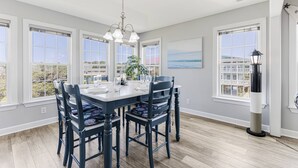 A dining room with a large table, chairs, and a chandelier. - Gorgeous 2nd Row Home with Amazing Ocean Views, 2 Large Decks, Dog Friendly, Sleeps 12 (Oak Island)