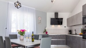 Eine moderne Küche mit Einbauherd, Mikrowelle und Backofen. Ein Esstisch mit Stühlen und eine Blumenvase sind ebenfalls vorhanden.