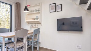 A modern kitchen with a dining area, a TV mounted on the wall, and a window with curtains. - 5 Star Holiday Home in Hovborg (Hovborg)