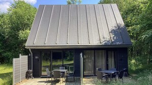 A modern building with a sloped roof, large glass doors, and outdoor seating. - 5 Star Holiday Home in Hovborg (Hovborg)