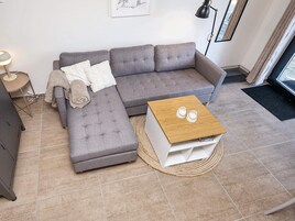 Una sala moderna con un sofá seccional gris, una mesita de centro de madera y un tapete redondo tejido.