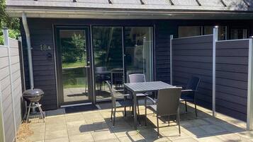A patio with a table and chairs, a barbecue grill, and a sliding glass door.