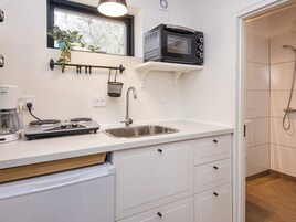 Una cocina moderna equipada con microondas, cafetera y lavamanos.