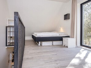 A bedroom with a bed, bedside table, and a window with a view. - 5 Star Holiday Home in Hovborg (Hovborg)
