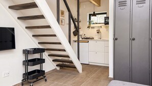 A staircase with wooden steps and a metal cart, a kitchen area with cabinets and a window, and a gray wardrobe. - 5 Star Holiday Home in Hovborg (Hovborg)
