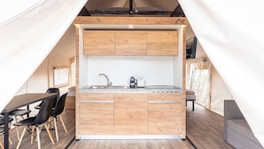 Une cuisine de taille réduite, dotée de meubles en bois, d’un évier et d’un coin repas avec des chaises.
