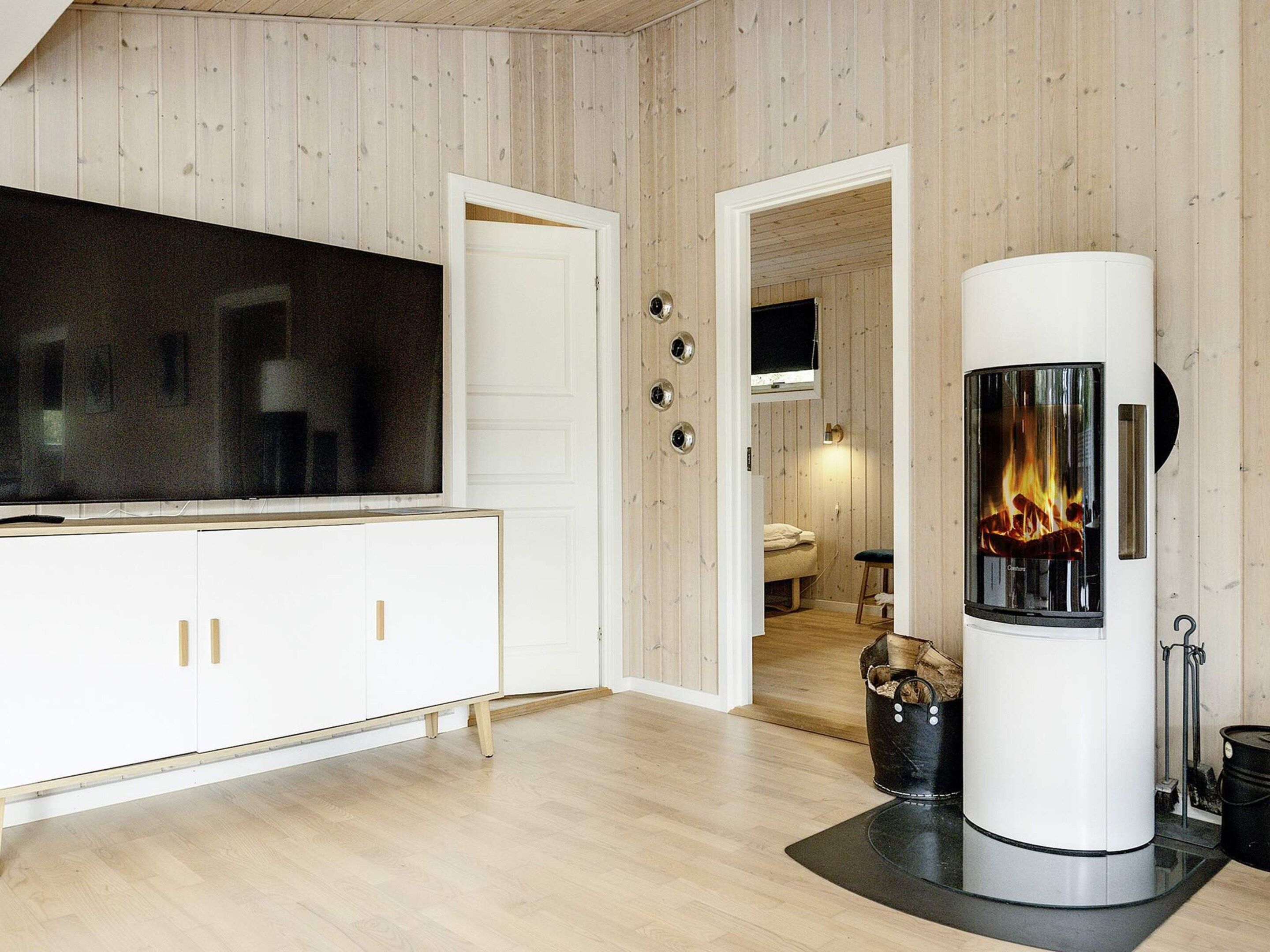 A modern living room with a flat-screen TV, white cabinets, a fireplace, and a cozy seating area.