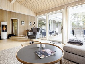 A modern living room with a fireplace, a round table with a magazine, and a cozy seating area. - 4 Star Holiday Home in Idestrup (Idestrup)