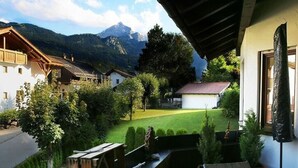 A balcony with a view of a mountain, a wooden deck, and a small garden area.