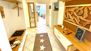 A hotel corridor with a wooden reception desk, a mirror, and a view into a dining area.