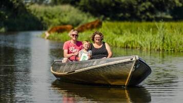 Una família en una barca estreta a un riu tranquil, envoltada de vegetació.