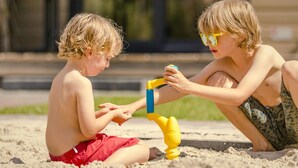 Due bambini giocano con un giocattolo su una superficie sabbiosa.