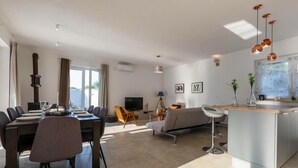 Un salon moderne comprenant un coin repas, un canapé, un téléviseur et un îlot de cuisine.