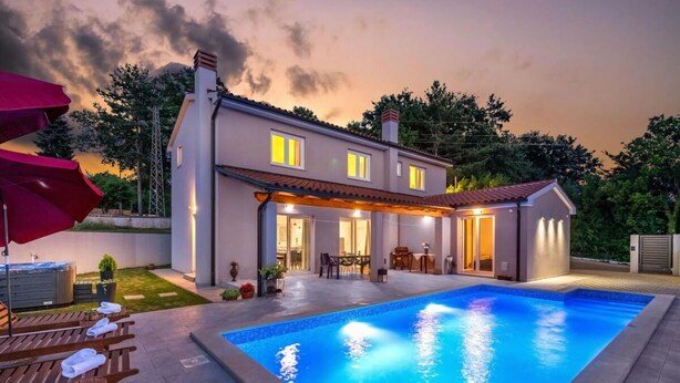 Une maison moderne à deux étages dotée d’une piscine, d’un espace salon extérieur et d’un patio couvert.