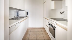 Eine moderne Küche mit weißen Schränken, einer Mikrowelle, einem Spülbecken und einem Backofen.