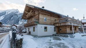 A wooden chalet with a balcony, a sign reading "HOLZ AU", and a mountain backdrop. - Comfortable Apartment in Salzburger Land (Neukirchen am Grossvenediger)