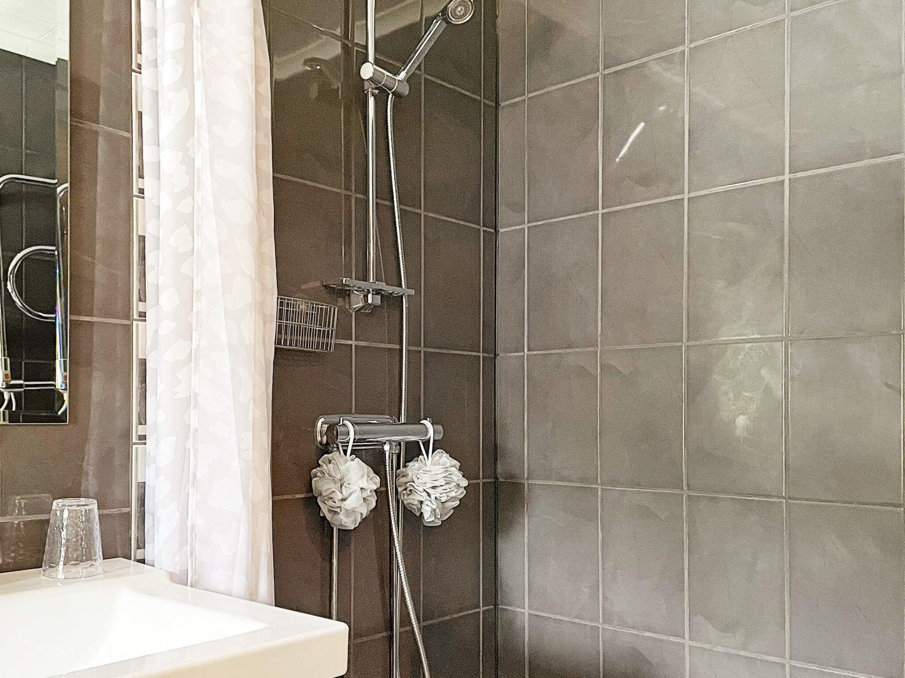 A bathroom with a shower, a sink, and a mirror.