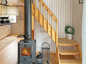 A cozy kitchen with a wood-burning stove, wooden staircase, and a potted plant. - 4 Person Holiday Home in Karlskoga (Karlskoga)