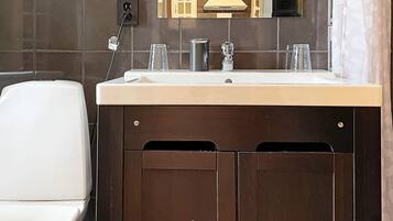 Een badkamer met een wit toilet, een wastafel met een spiegel erboven en een donker houten kast eronder.