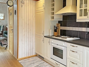 A kitchen with white cabinets, a stove, and a clock on the wall.