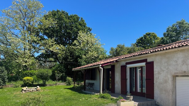 Una casa de planta baixa amb teulada de rajola, un porxo i una petita zona de jardí.