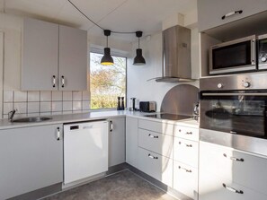 A modern kitchen with white cabinets, stainless steel appliances, and pendant lighting. - 8 Person Holiday Home in Lemvig-by Traum (Lemvig)