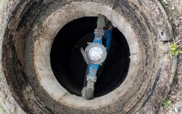 Een cirkelvormige constructie met een centraal metalen object, mogelijk een ventiel of een pomp, omgeven door een betonnen ring.