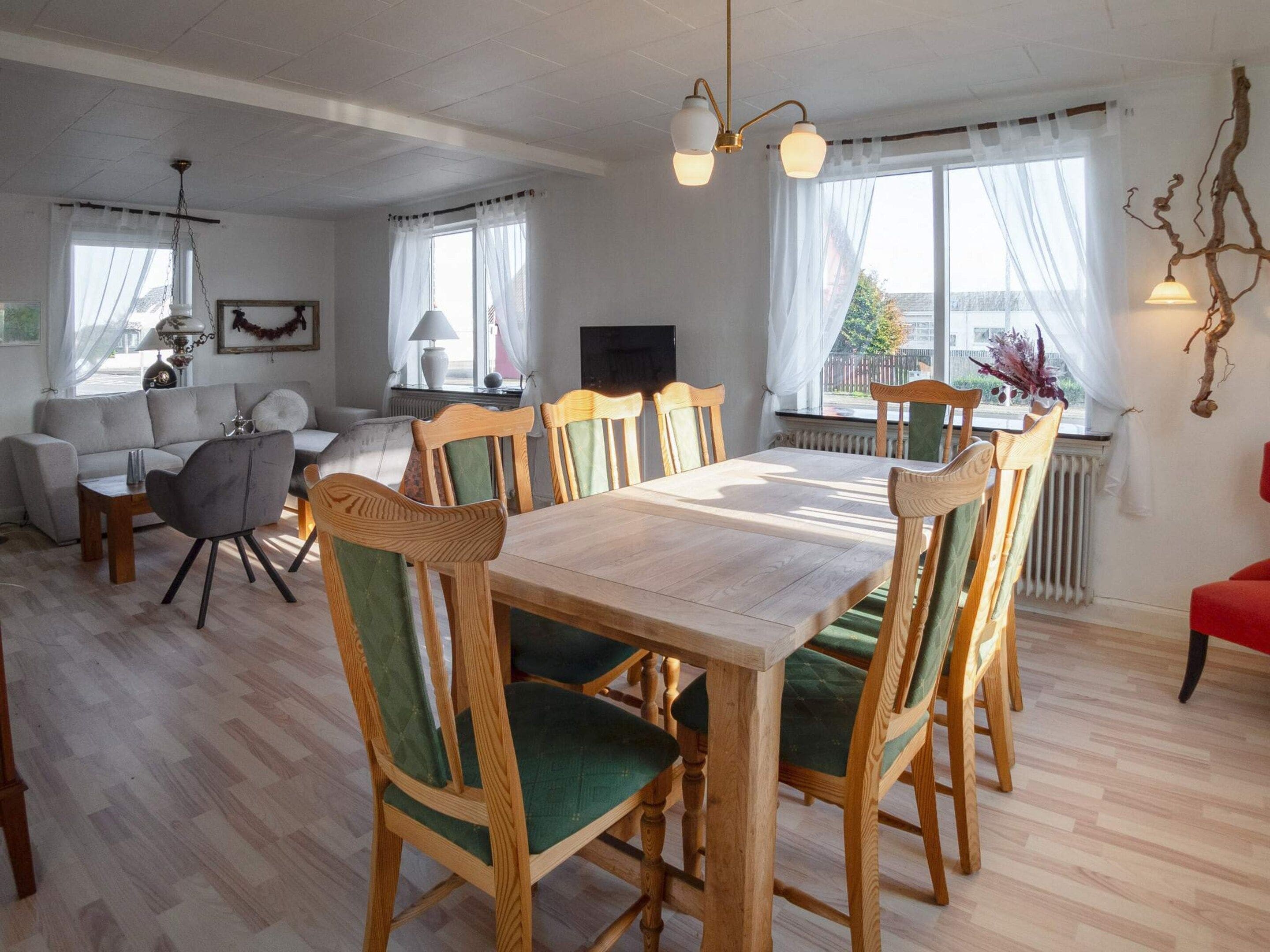 Un comedor con una mesa y sillas de madera, un sofá y una televisión.