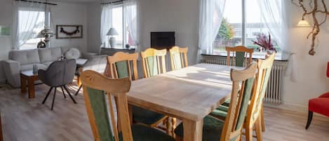 A dining area with a wooden table and chairs, a sofa, and a television.