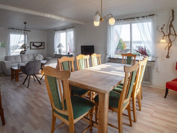 A dining area with a wooden table and chairs, a sofa, and a television.